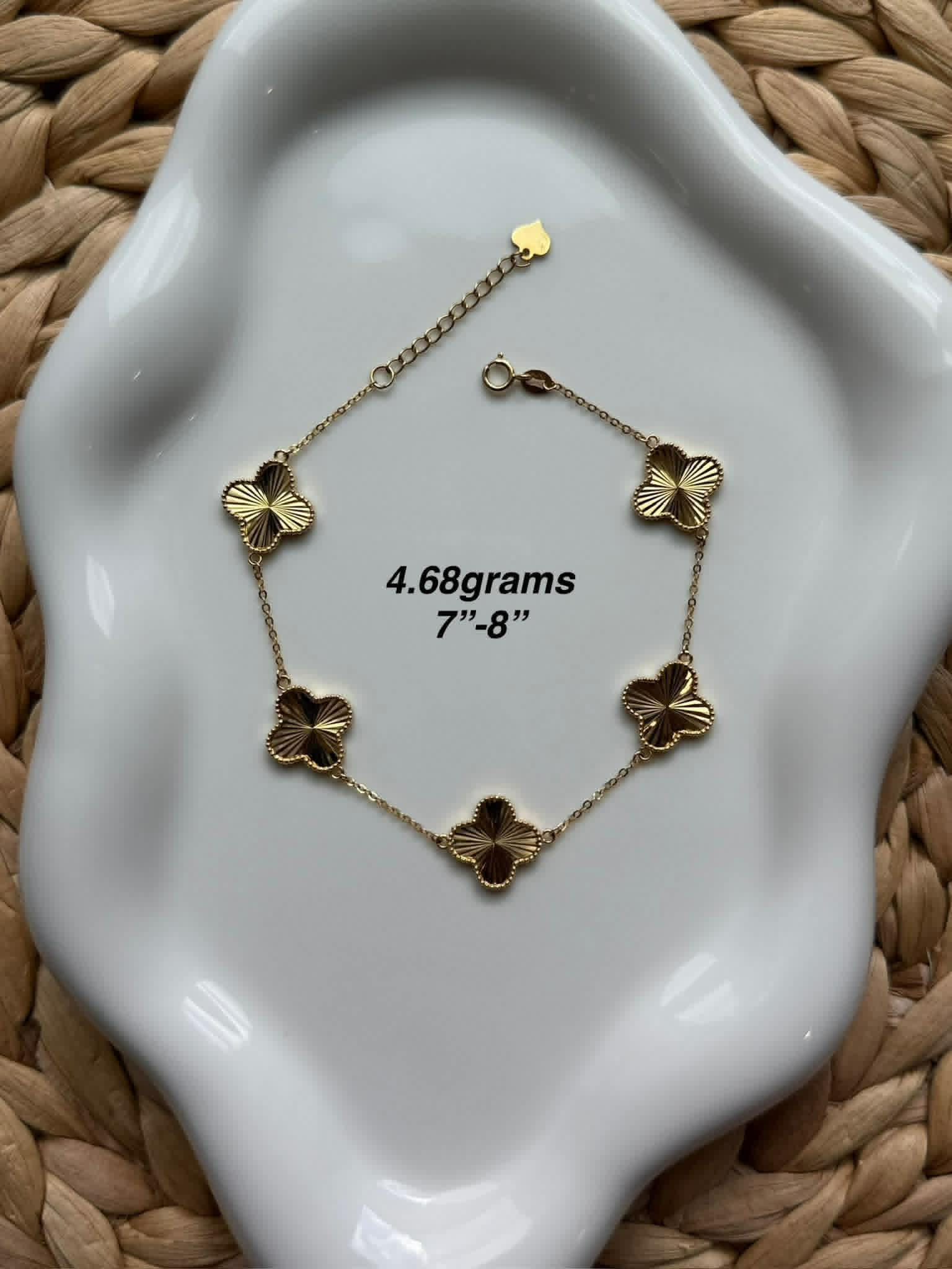 Gold clover station bracelet on a ceramic dish