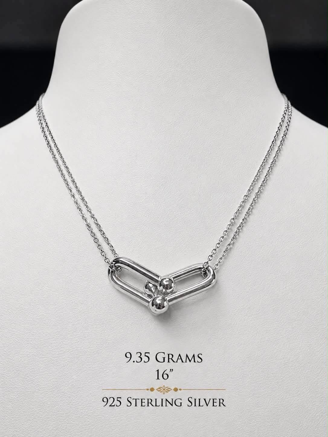Sterling silver link necklace with a ball-and-bar clasp centre, on a display bust