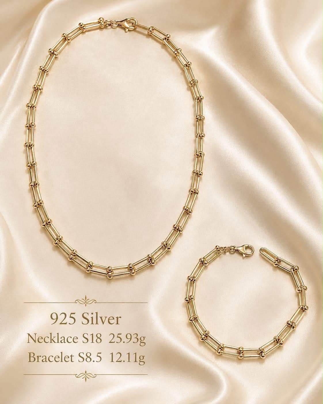 Gold-tone bar and ball link necklace with matching bracelet on cream silk